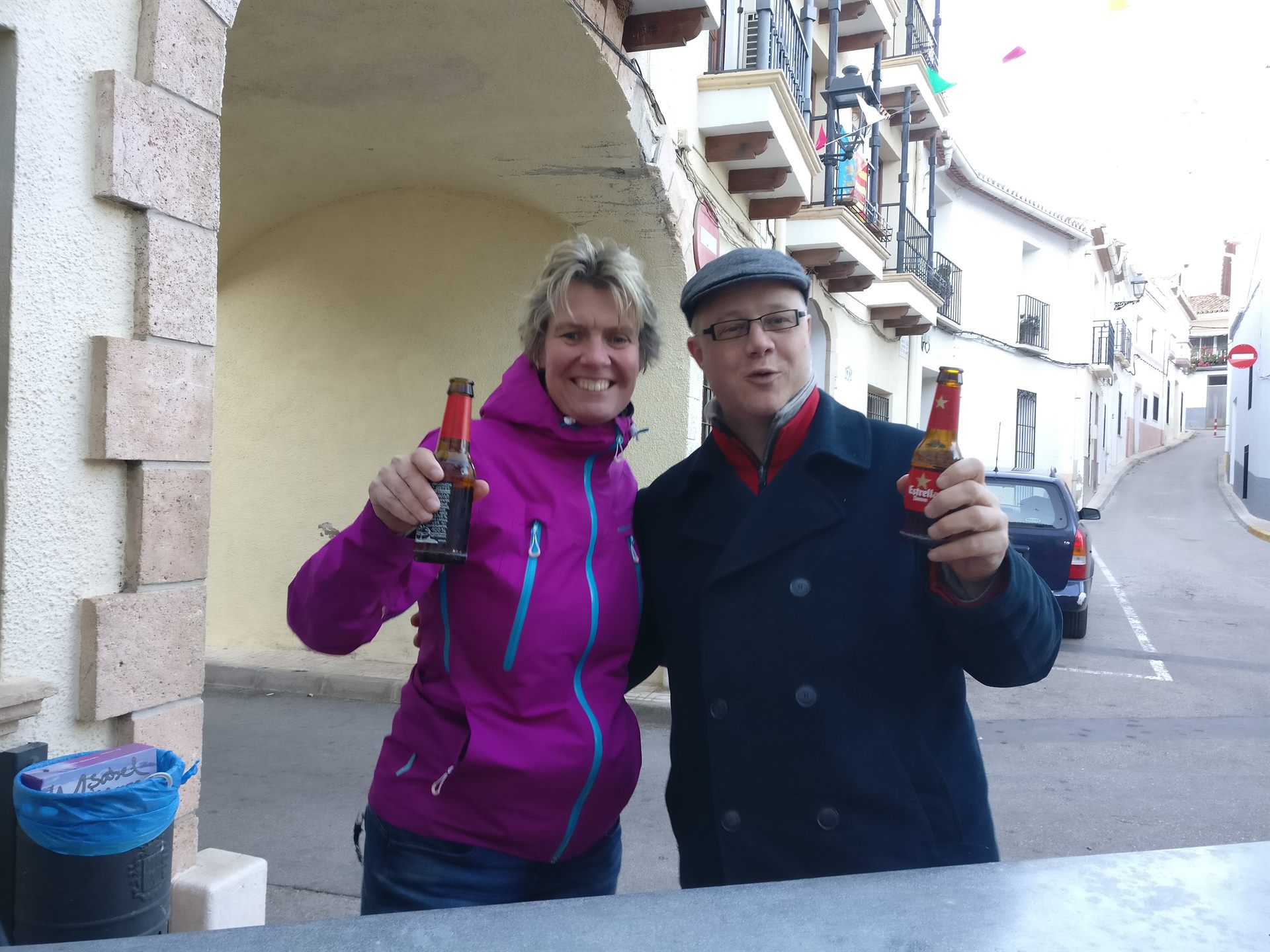 Una mujer y un hombre brindando con una cerveza en una calle de un pueblo español